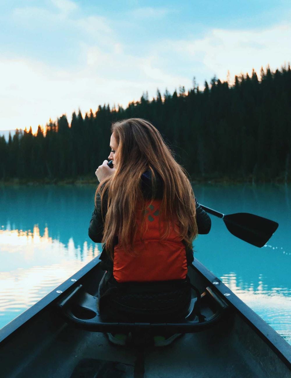 A person paddling out across a still lake at first light